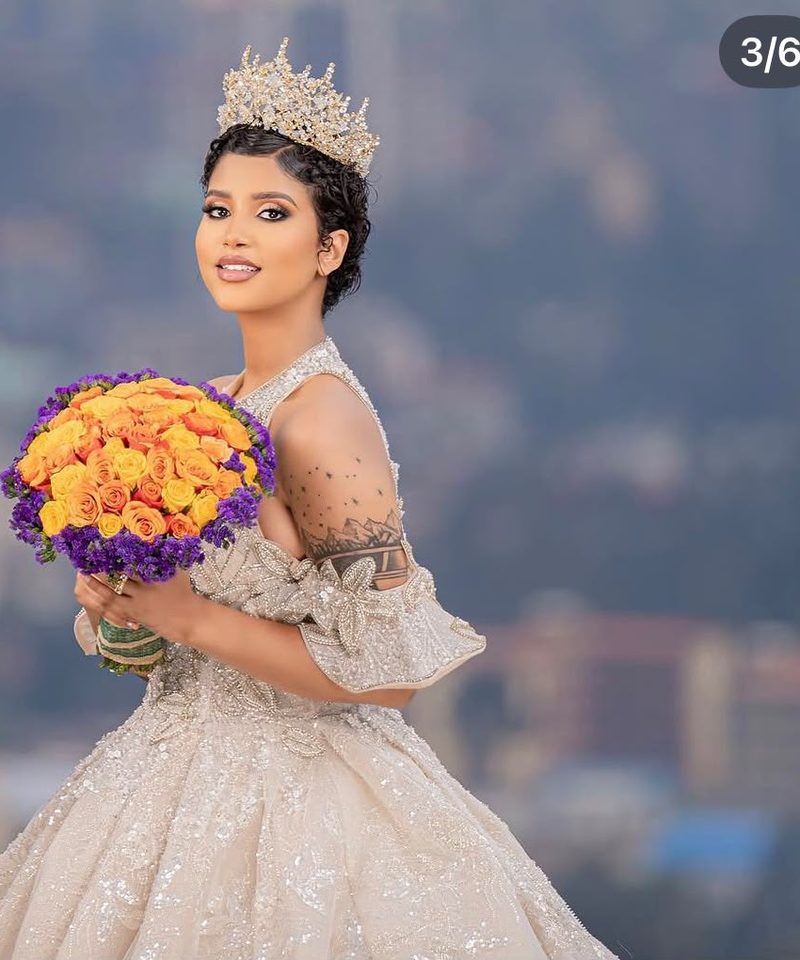 Bride in beaded ball gown wearing a jeweled crown holding a bouquet