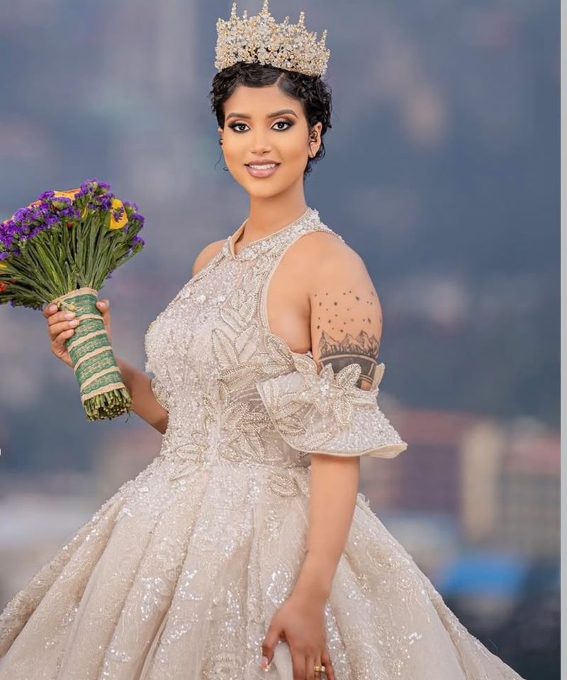 Bride with jeweled crown and beaded gown posing with bouquet at golden hour
